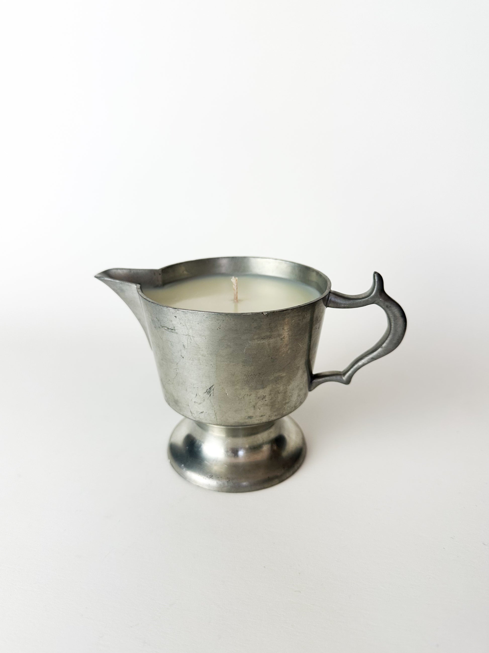 Metal pitcher candle on a white background