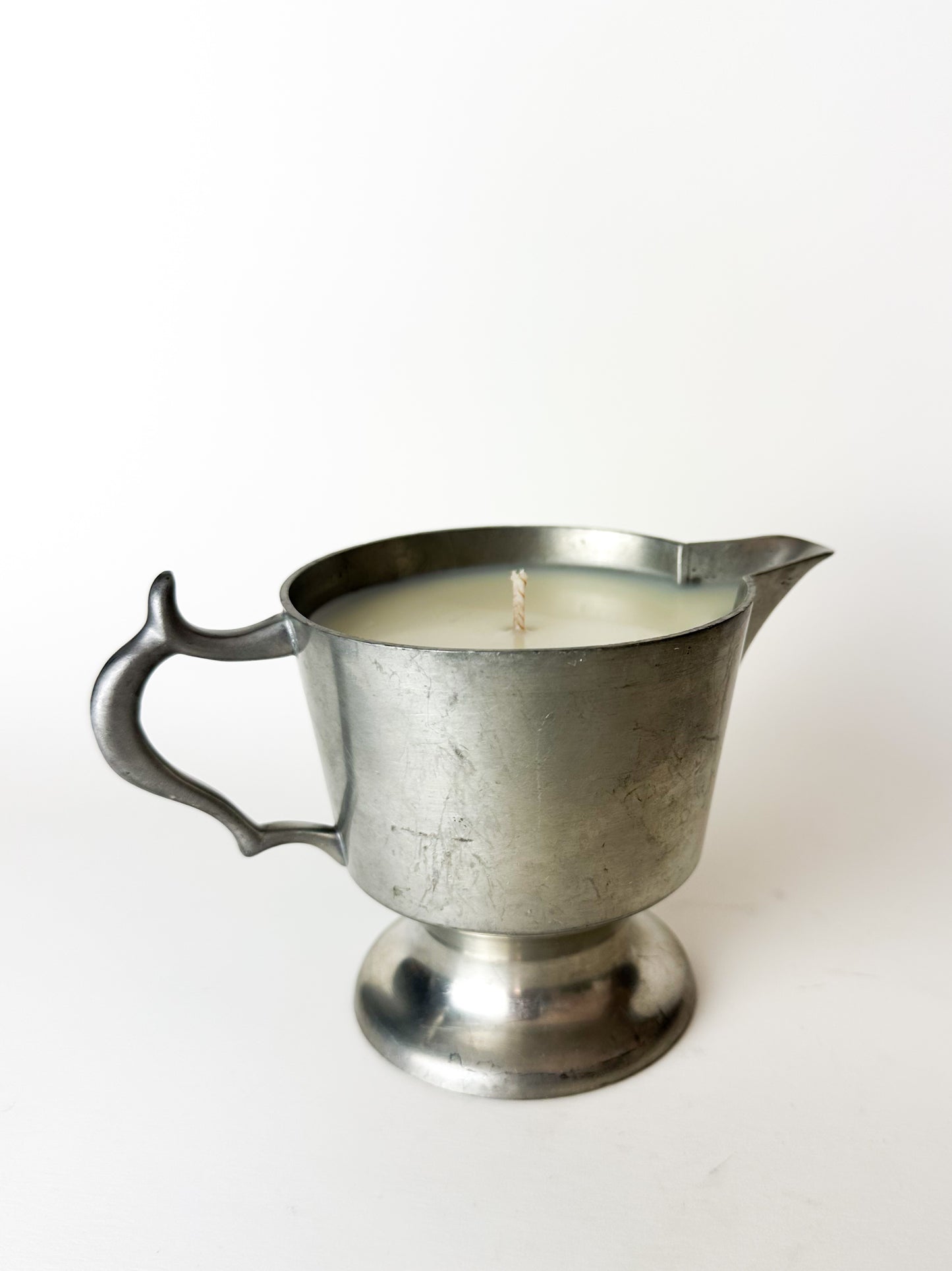 Metal pitcher candle on a white background