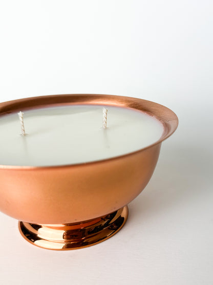 Copper bowl with a white candle on a white background