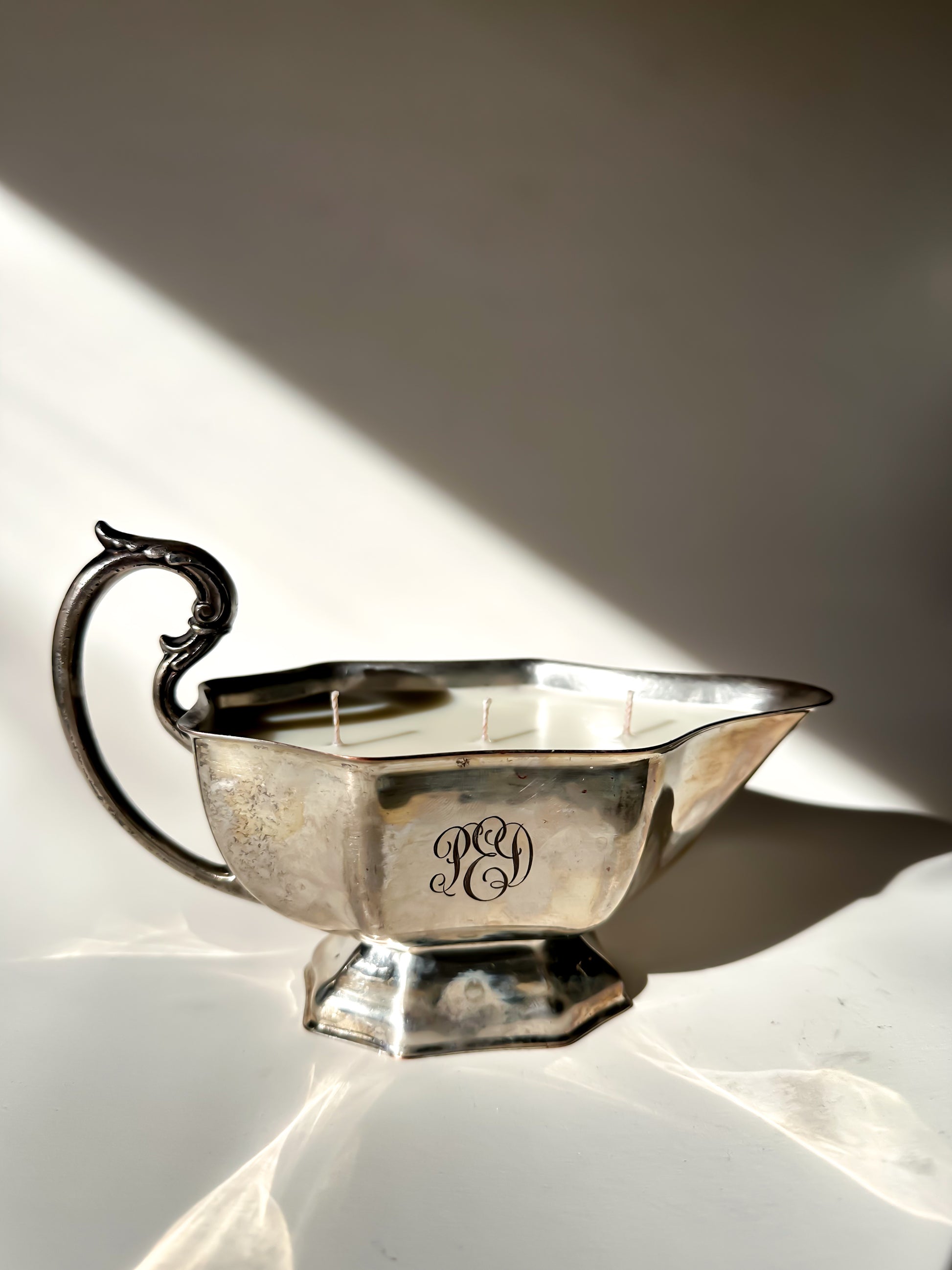Silver gravy boat with monogram on a white surface