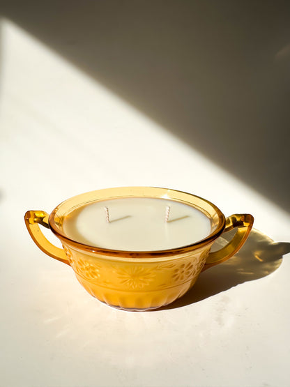 Vintage-style amber glass bowl with a candle inside, casting a shadow on a light background