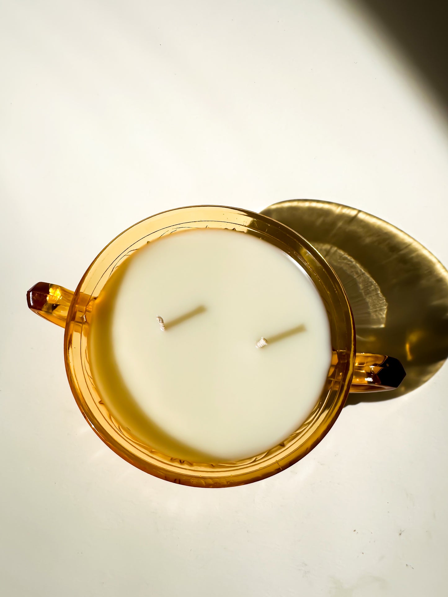 Candle in a decorative amber glass bowl on a light background
