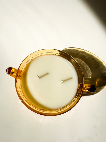 Candle in a decorative amber glass bowl on a light background
