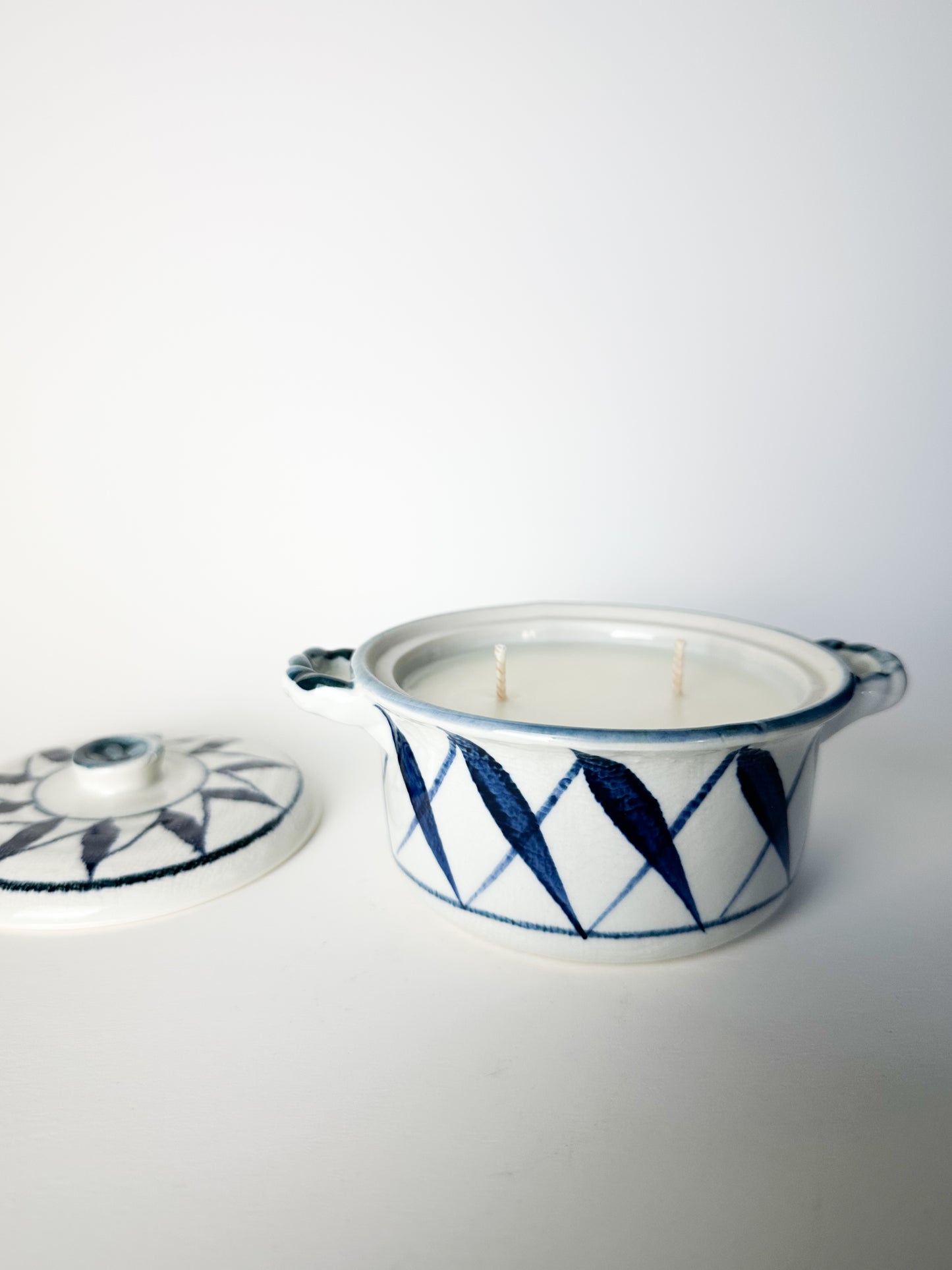 Ceramic container with a lid featuring blue geometric patterns on a white background