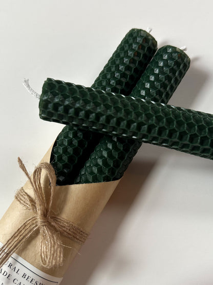 Three green textured candles on a white background with a roll of paper.