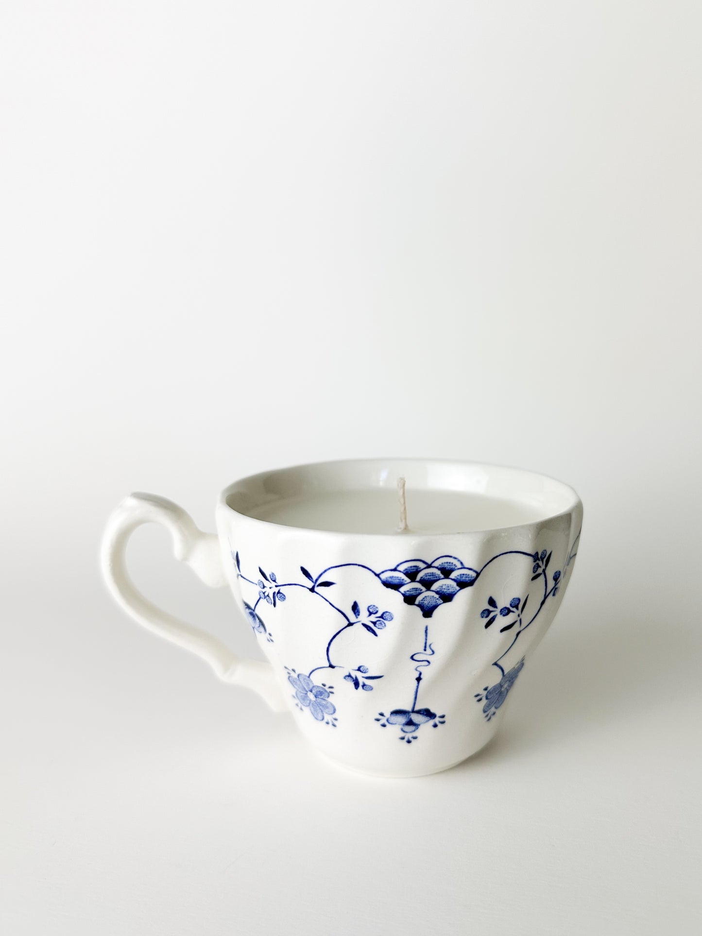 White ceramic mug with blue floral patterns on a white background