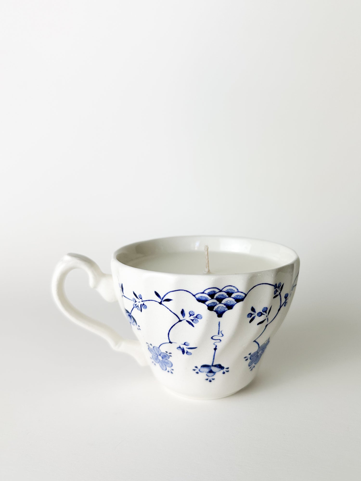White ceramic mug with blue floral patterns on a white background