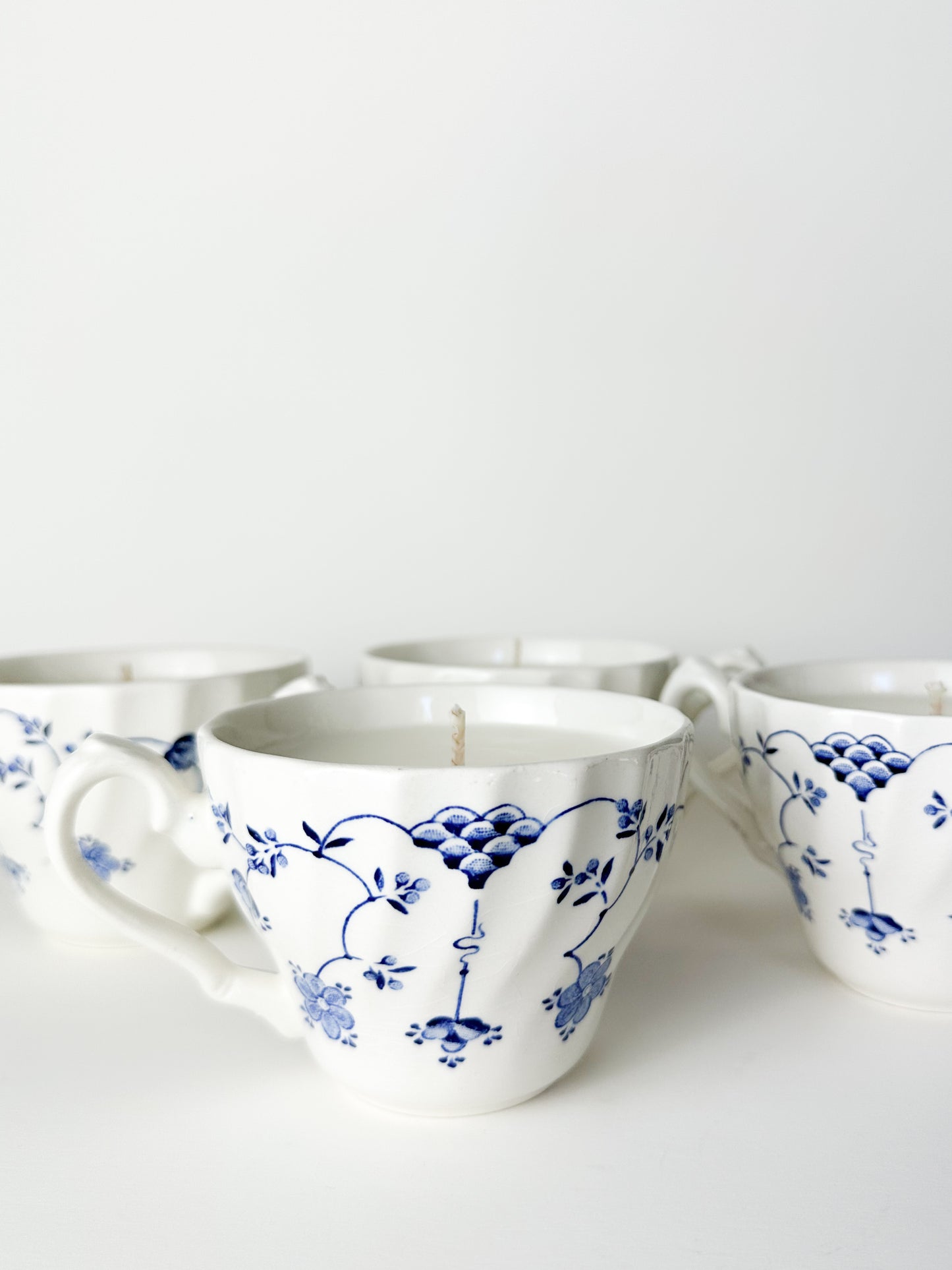 White ceramic cups with blue floral patterns on a white background