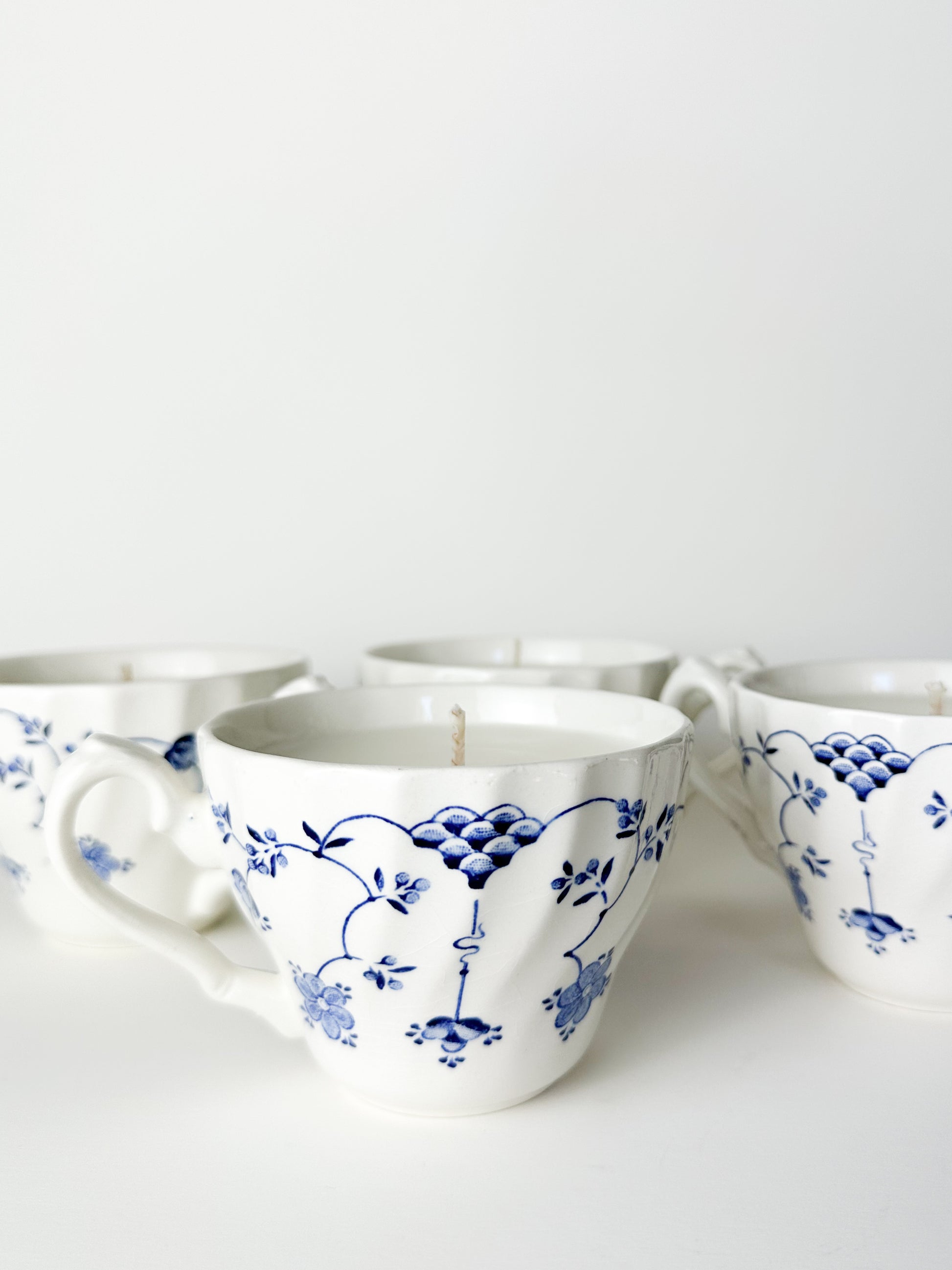White ceramic cups with blue floral patterns on a white background