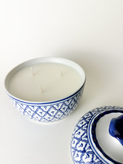 Ceramic container with a candle inside, featuring blue patterns on a white background
