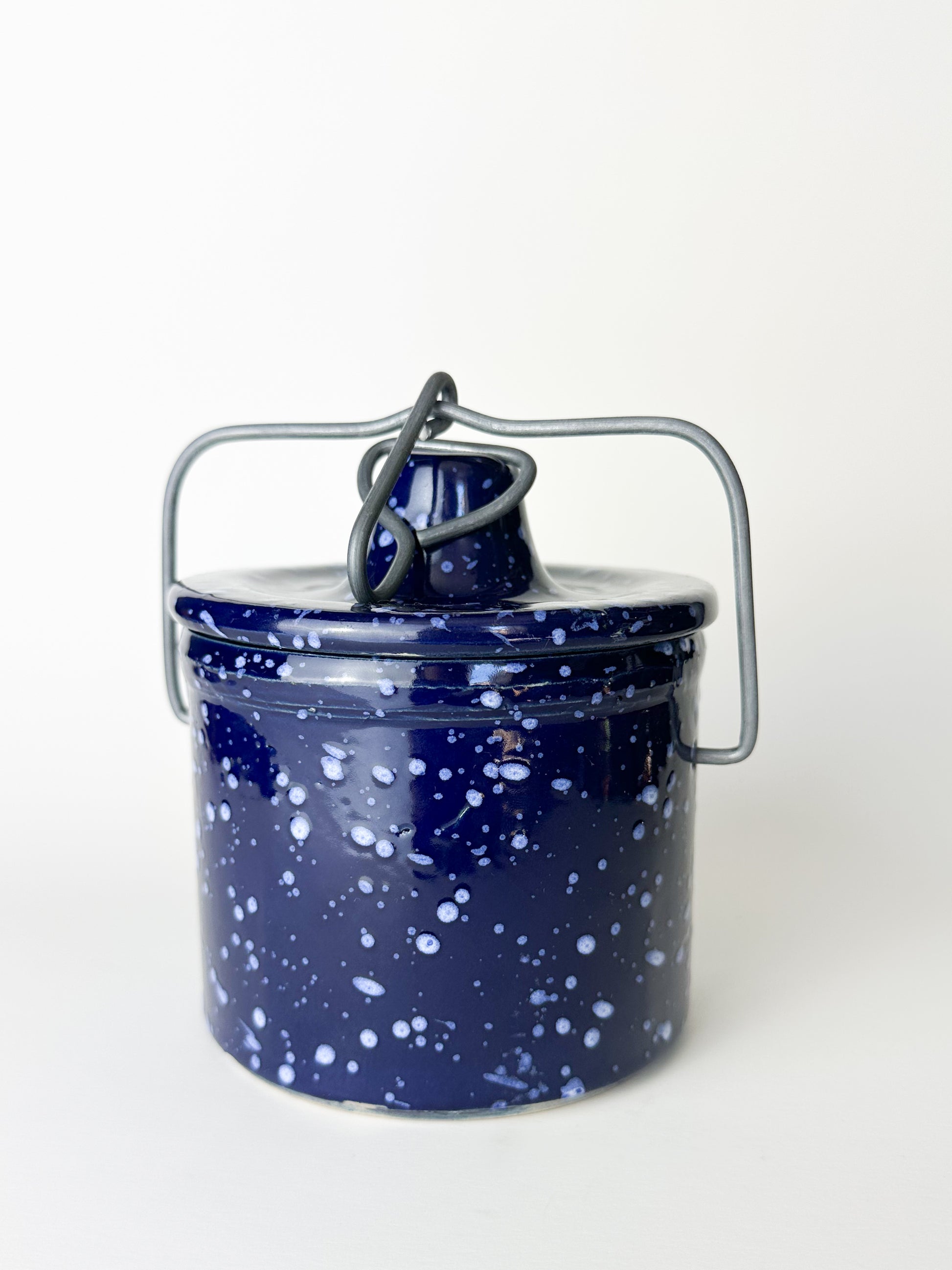 Blue speckled enamel canister with a metal handle on a white background