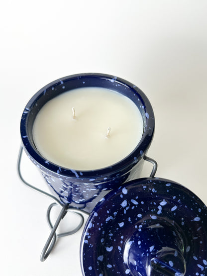 Candle in a blue speckled container on a white background
